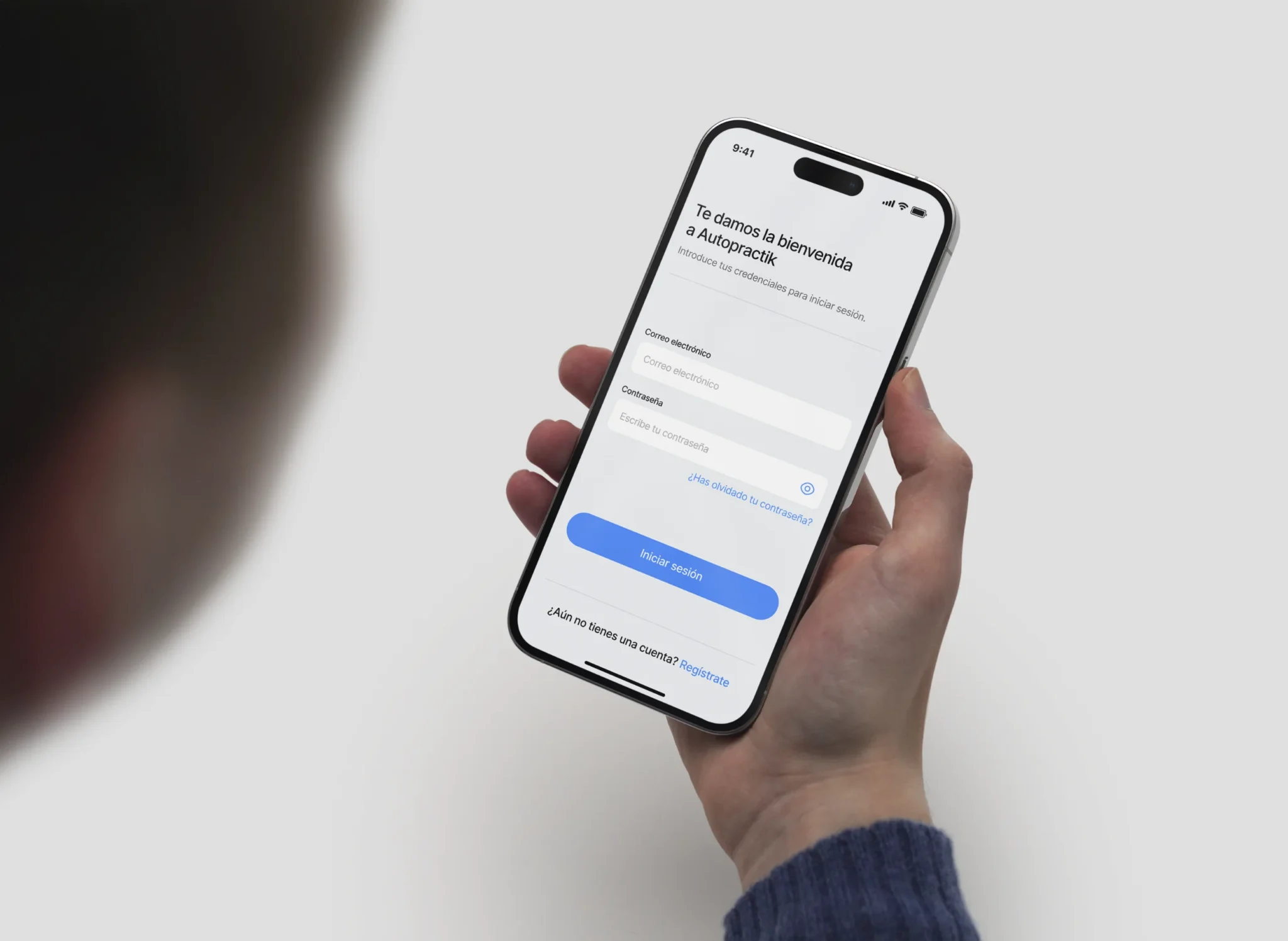 Mano sosteniendo un smartphone con la pantalla de inicio de sesión de la aplicación Autopractik, diseño de interfaz por Jorge ML.