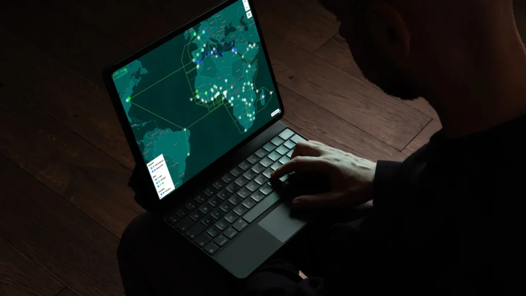 Operador gestionando la infraestructura de red global mediante un dashboard interactivo en tablet con visualización de mapa oscuro.